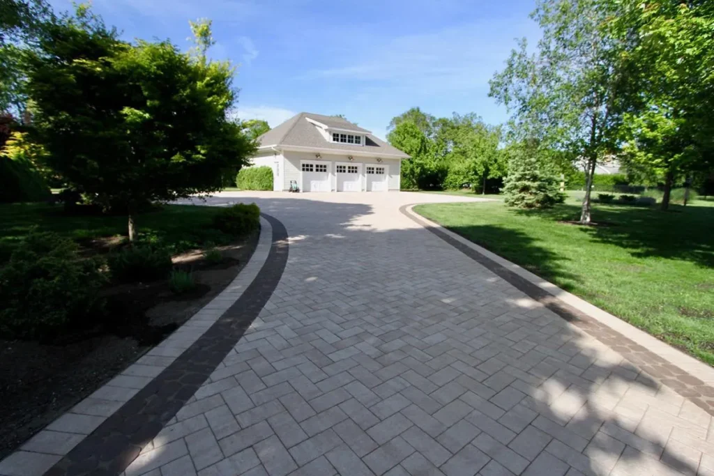 Long paver driveway framed by professional landscaping