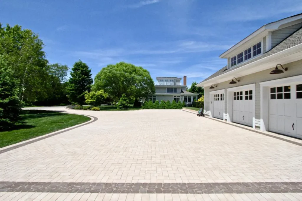 Curved custom paver driveway leading to a three-car garage