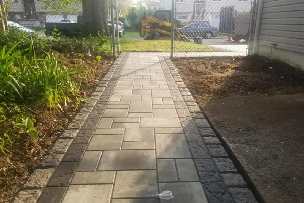Paver walkway leading to a backyard patio