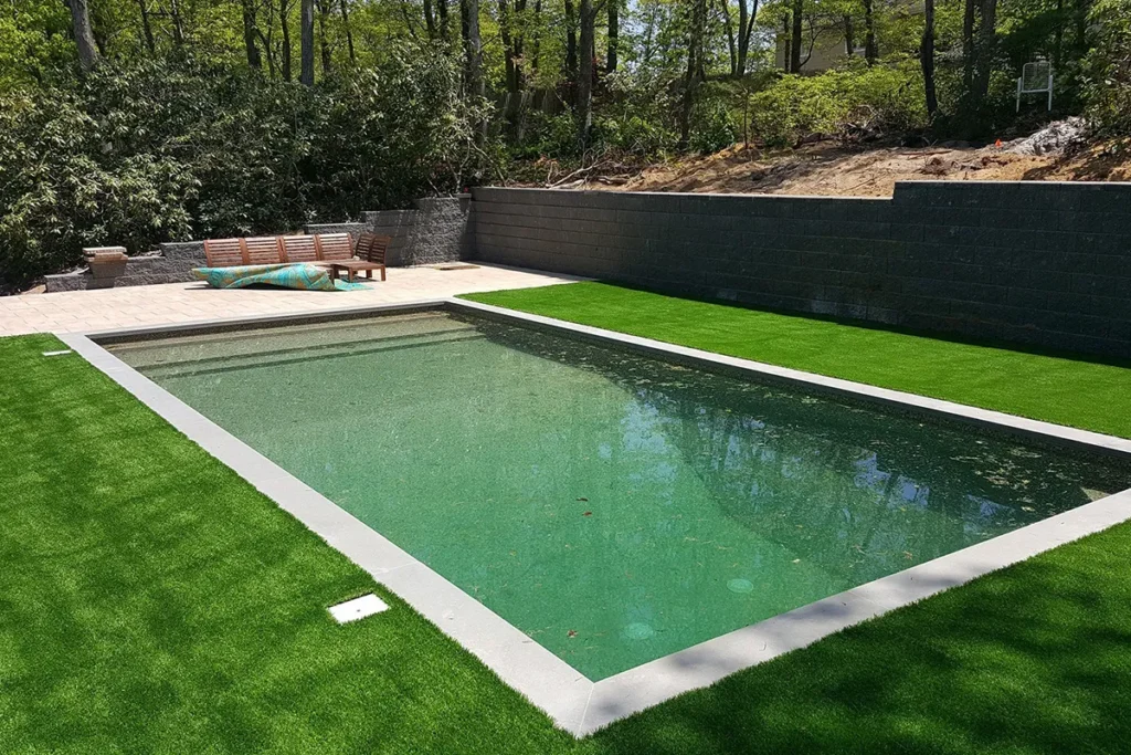 Inground pool with dark liner and artificial turf surround