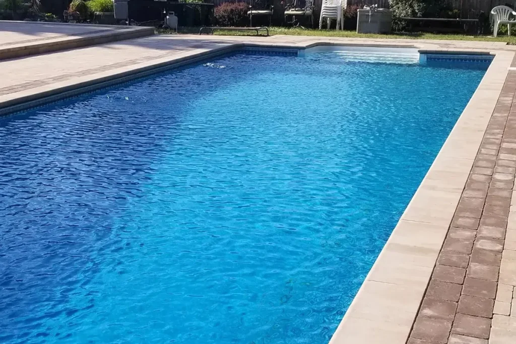 Rectangular inground pool with tan paver deck, detail view